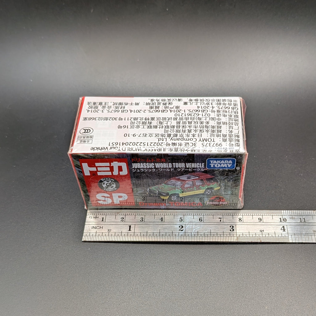 
Takara Tomy Dream Tomica SP Jurassic World Tour Vehicle (Ford Explorer), 1/64 scale diecast boxed and unopened. The picture is taken from slightly above and in front of the box, the metal ruler beside it shows a length of 8cm. Displayed on a black background