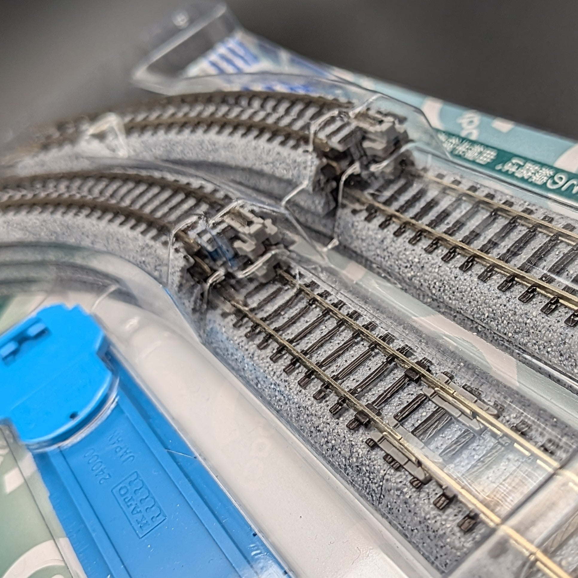 Kato CV1 Unitrack Compact Track Set (model 20-890) in its original packaging, featuring a close up of some of the grey track pieces and sat on a black background.