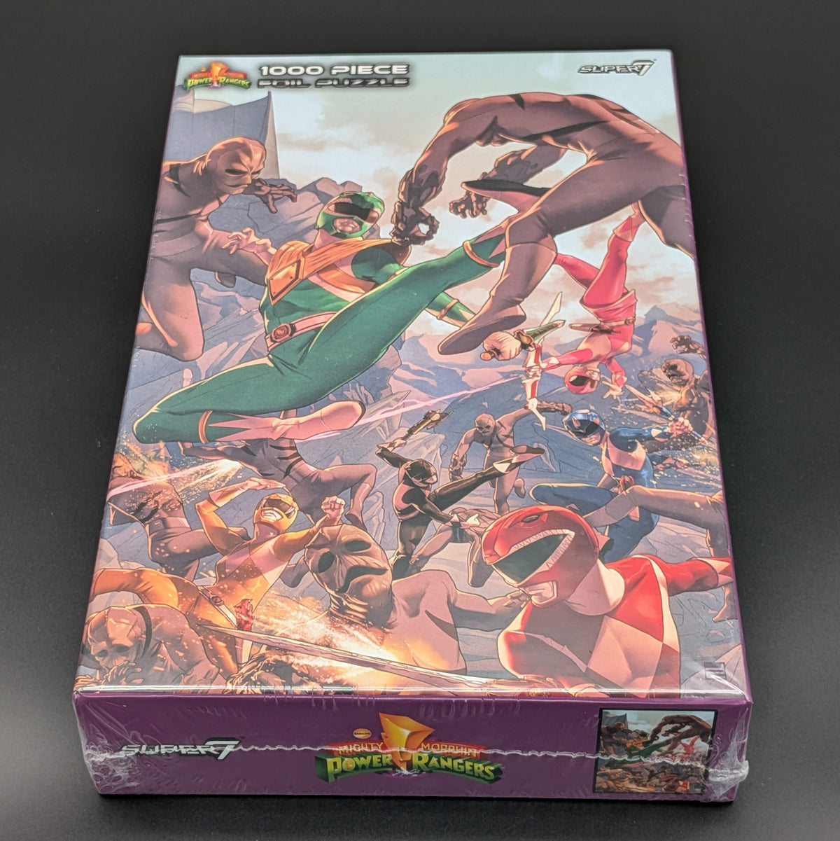 A 1000-piece Power Rangers jigsaw puzzle from Super7, still sealed in its original purple plastic shrink wrap. The box features a highly detailed, colorful illustration of the Power Rangers team in action.