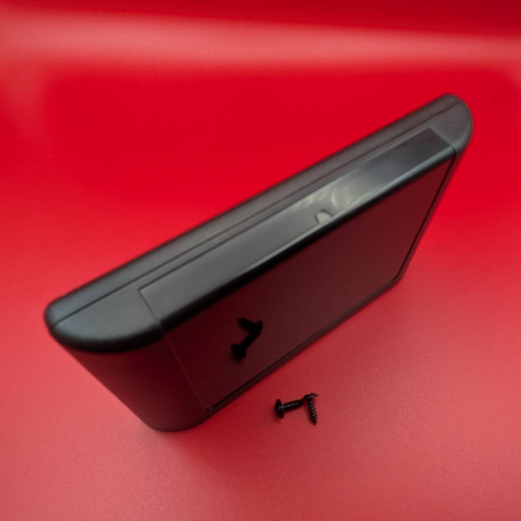 A black plastic video game cartridge case. Shown at an angle on a vibrant red background with small black screws in front of it.