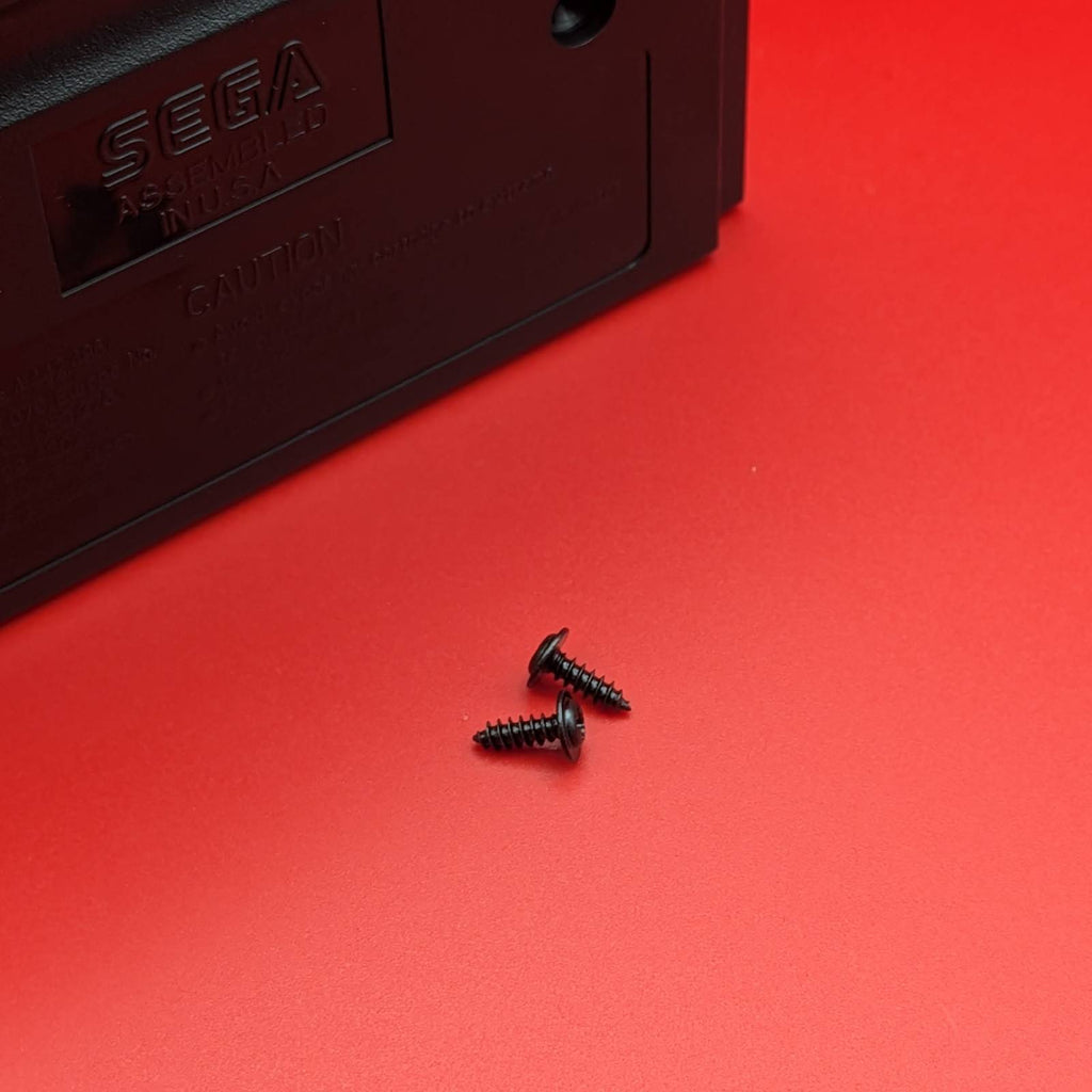 Two small black screws placed on a bright red surface next to a dark plastic component with embossed SEGA branding.