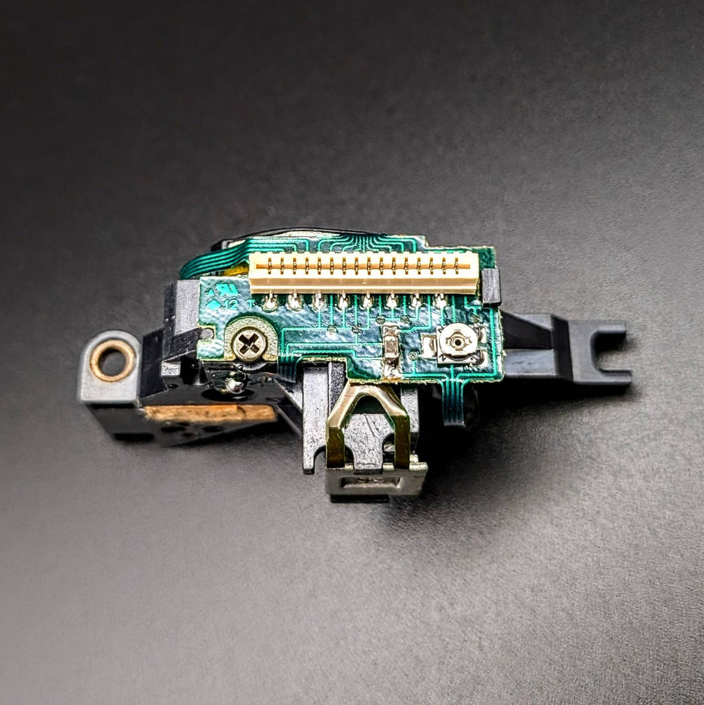A replacement electronic connector module with a green circuit board, gold-plated pins, and black plastic housing, photographed on a dark gray background.