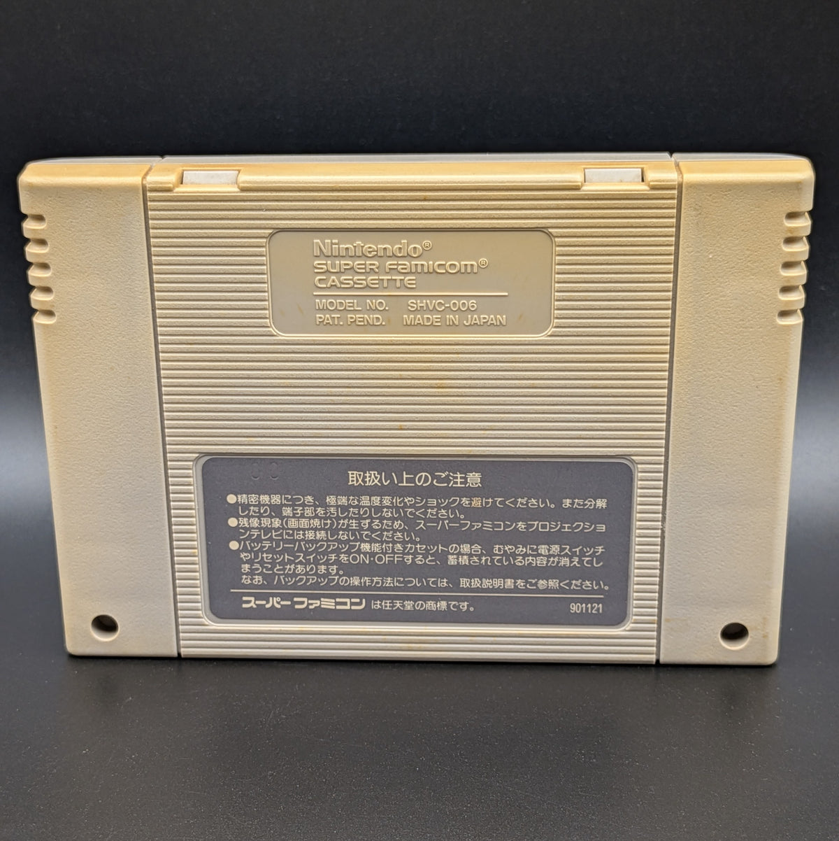 Sim City video game cartridge for Nintendo's Super Famicom (SFC) Entertainment System, showing the back of the cartridge. It sits on a dark grey background.