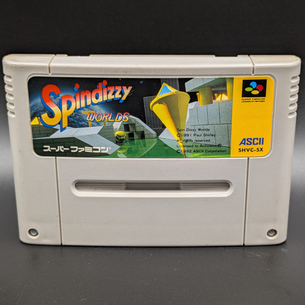 A close up of Spindizzy Worlds video game cartridge for Nintendo's Super Famicom (SFC) Entertainment System, shown standing up and facing forward on a dark grey background.
