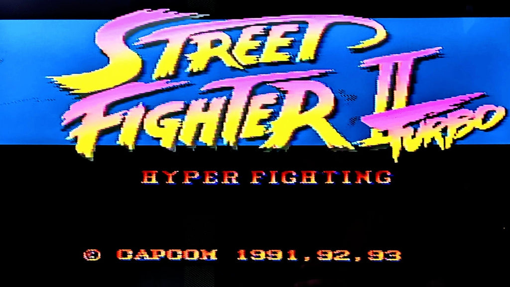 Title screen of 'Street Fighter II Turbo: Hyper Fighting' with colourful text on a blue background. This shows the game in working order.
