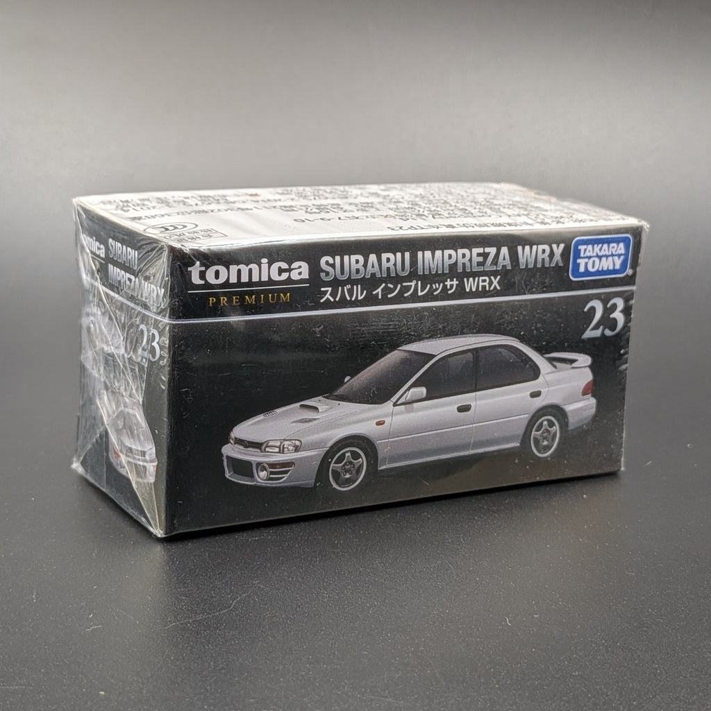 A Takara Tomy model car sealed in its packaging. This Tomica premium model shows a Subaru Impreza WRX on the front of the packaging which is sat on a dark grey background.