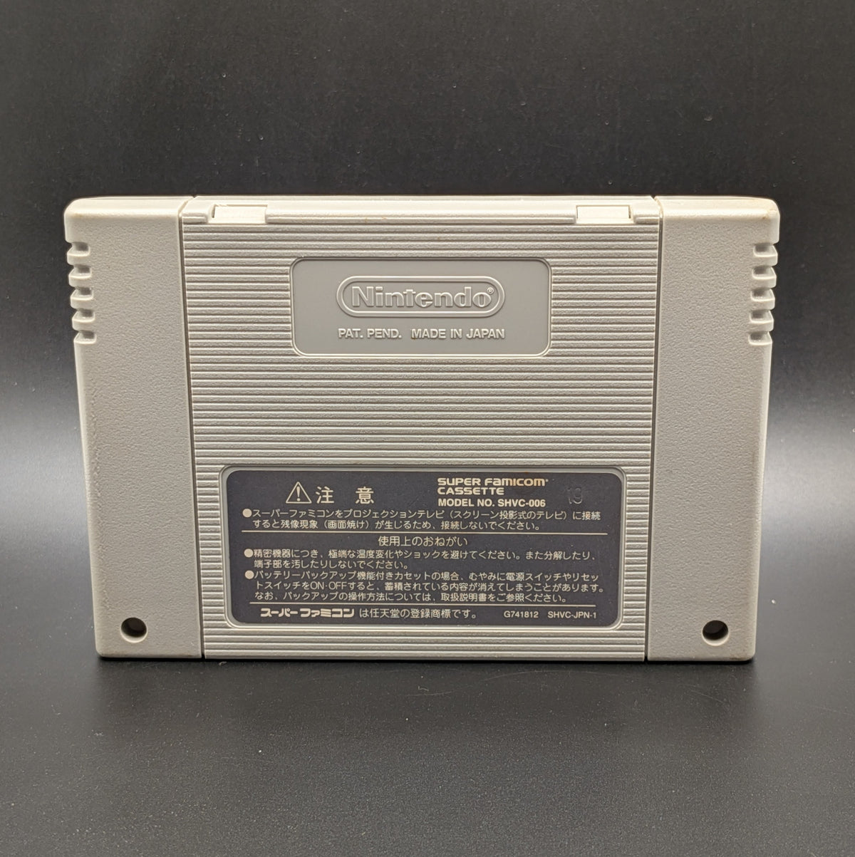Super Bomberman 4 video game cartridge for Nintendo's Super Famicom (SFC) Entertainment System, showing the back of the cartridge. It sits on a dark grey background.
