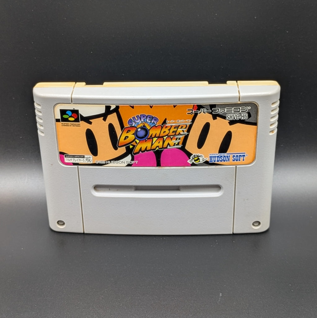 Super Bomberman video game cartridge for Nintendo's Super Famicom (SFC) Entertainment System, shown standing up and facing forwards on a dark grey background.
