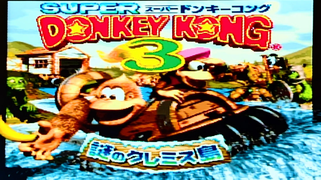 Japanese digital title screen for Donkey Kong 3 for the Super Famicom, featuring Dixie Kong and Kiddy Kong in a raft on water, with the title 'SUPER Donkey Kong 3' at the top and Japanese text at the bottom. Photo taken to show the game has been tested.