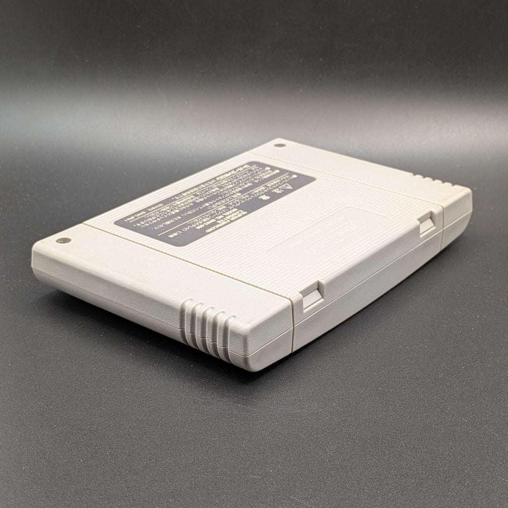 Donkey Kong 2 video game cartridge for Nintendo's Super Famicom (SFC) Entertainment System, shown laying on its front and facing down, on a dark grey background.
