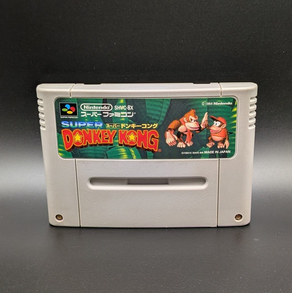 Super Donkey Kong video game cartridge for Nintendo's Super Famicom (SFC) Entertainment System, shown standing up and facing forward on a dark grey background.
