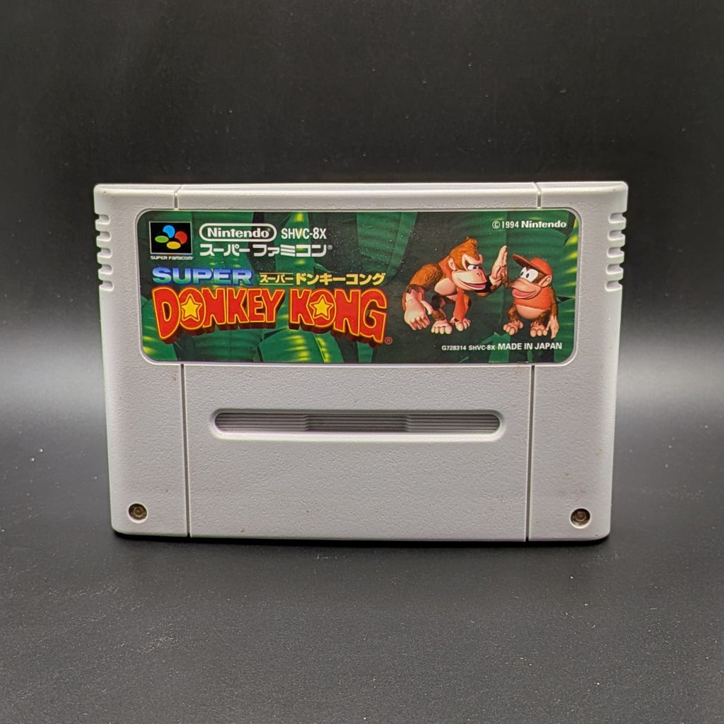 Super Donkey Kong SHVC-8X video game cartridge for the Super Famicom Entertainment System, shown standing up and facing forward on a dark gray background.