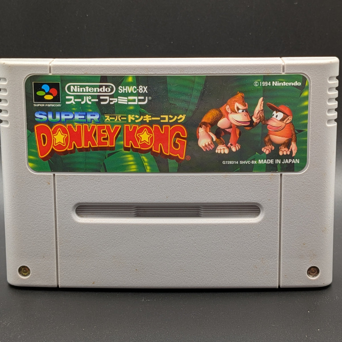 Nintendo Super Famicom Donkey Kong SHVC-8X retro game cartridge, featuring the original Japanese label with Donkey Kong and Diddy Kong artwork on a gray plastic case.