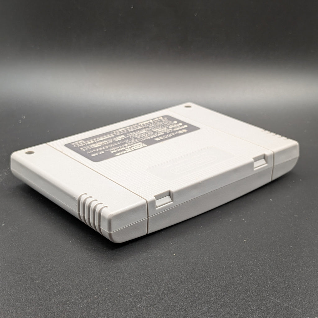 Super Donkey Kong SHVC-8X video game cartridge for the Super Famicom Entertainment System, shown laying on its front, at a 3/4 angle facing down so the back label is visible. Pictured on a dark grey background.