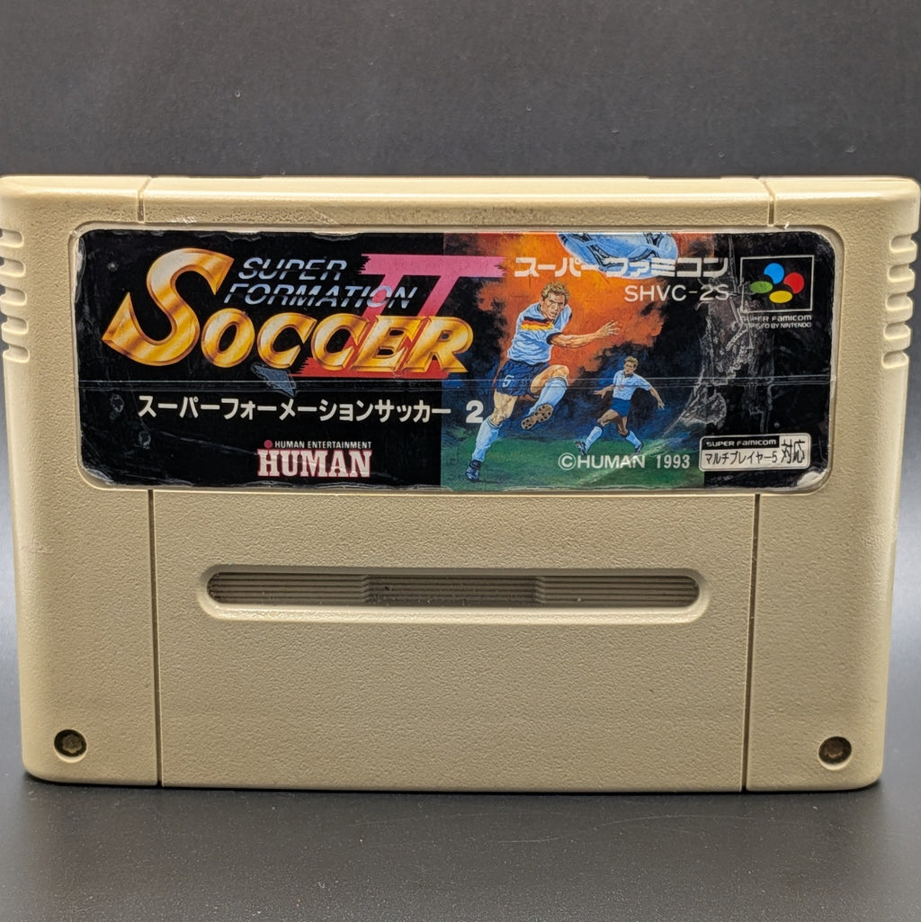 A close up of Super Formation Soccer 2 video game cartridge for Nintendo's Super Famicom (SFC) Entertainment System, shown standing up and facing forward on a dark grey background.
