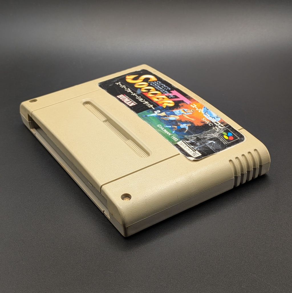 Super Formation Soccer 2 video game cartridge for Nintendo's Super Famicom (SFC) Entertainment System, shown laying down  on its back, on a dark grey background.
