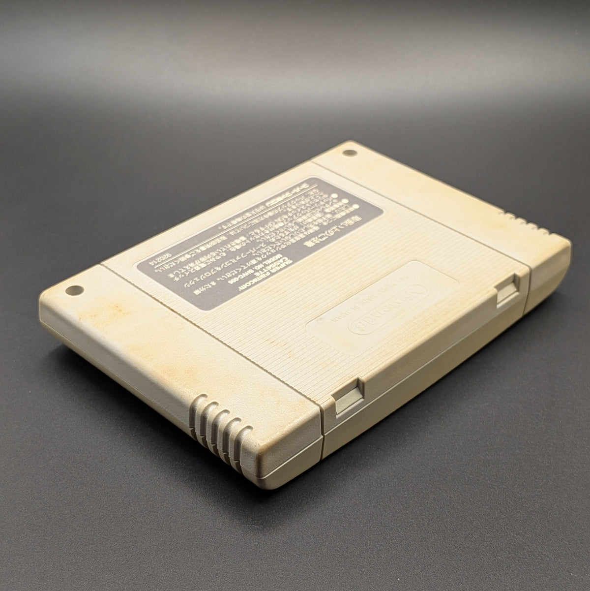 Super Formation Soccer 2 video game cartridge for Nintendo's Super Famicom (SFC) Entertainment System, shown laying down on its front, on a dark grey background.
