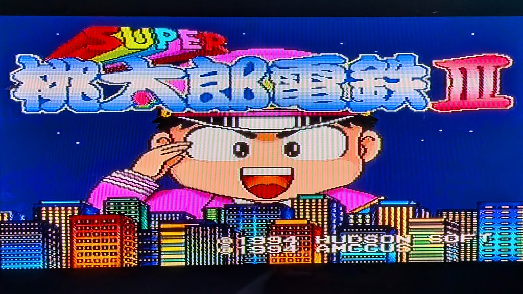 The game title screen for Super Momotarou Dentetsu 3, for Nintendo's Super Famicom (sfc) showing a cartoon character in front of a colorful city skyline on a dark blue background. This is to show the game is tested and working.