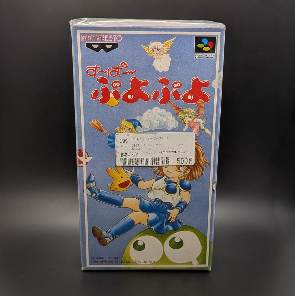 Super Puyo Puyo boxed and sealed video game cartridge for Nintendo's Super Famicom (SFC) Entertainment System, shown standing face on, on a dark grey background. There is a Japanese store sticker stuck to the front on the outer packaging.
