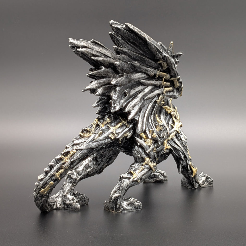 A detailed fantasy creature figurine with a textured, bark-like body, metallic silver-gray scales, and small gold accents, standing on a dark surface against a gray gradient background.