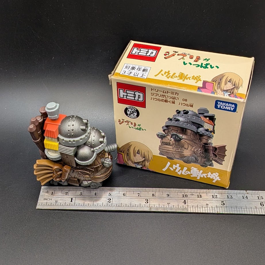 Howls Moving Castle Tomica Dream  Model No.8 - Full view of the model next to its box and a ruler for scale on a dark gray background.