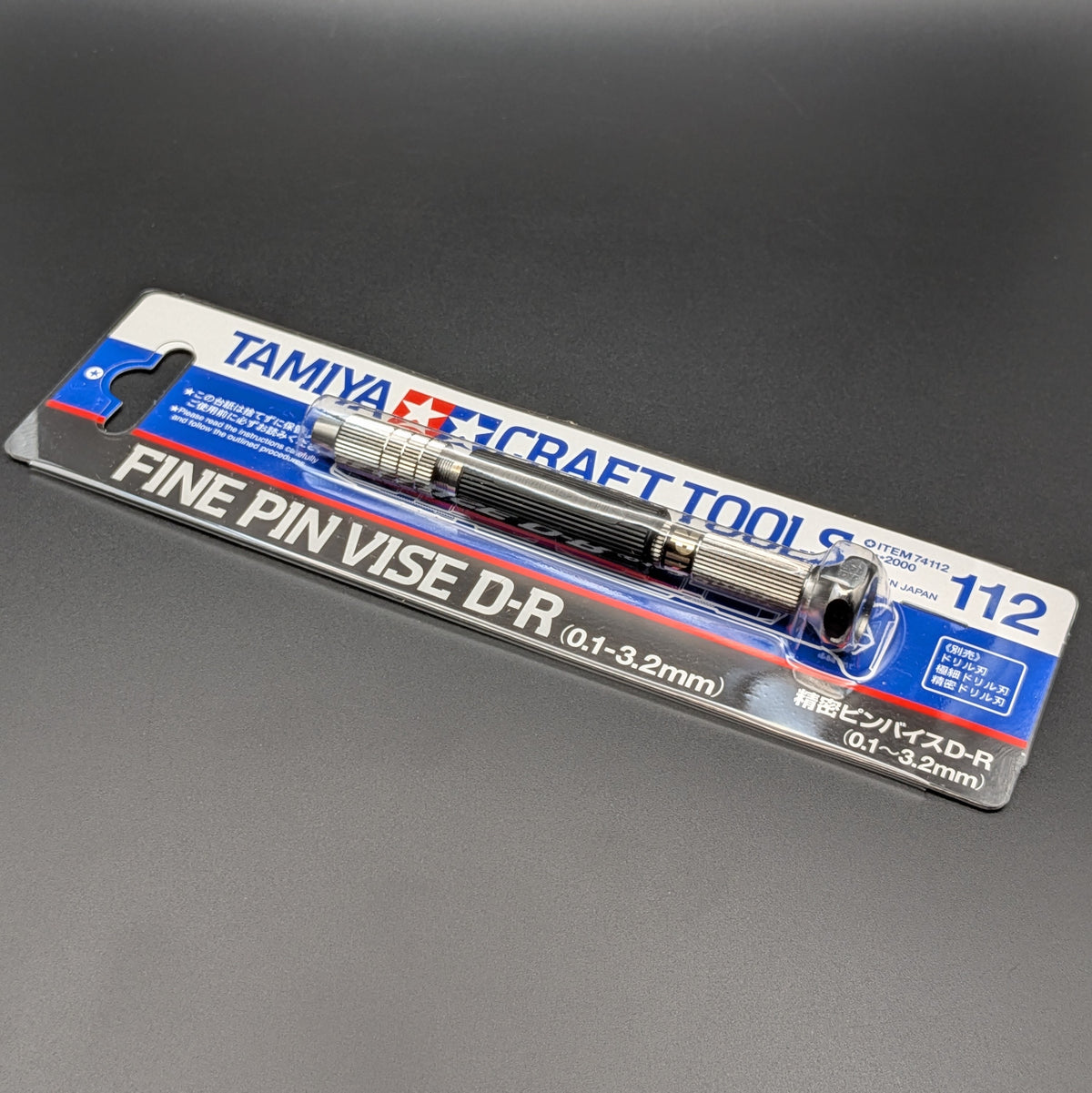 Tamiya 74112 Fine Pin Vise D-R (0.1-3.2mm) in its original blister card packaging, displayed on a dark gray background.