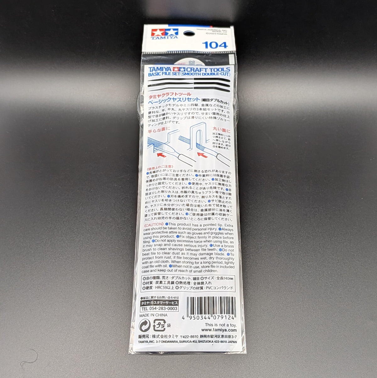 Tamiya Craft Tools Basic File Set (Smooth Double-Cut) model kit tool 74104 showing the back of the retail packaging, displaying the information in Japanese on the back. This is on a dark grey surface.
