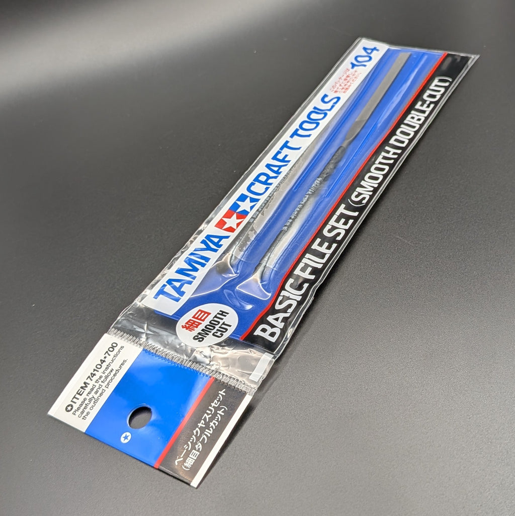 Tamiya Craft Tools Basic File Set Smooth Double-Cut No. 104 in its original retail packaging, displayed at an angle, leaning to the right and laying on a dark grey surface.