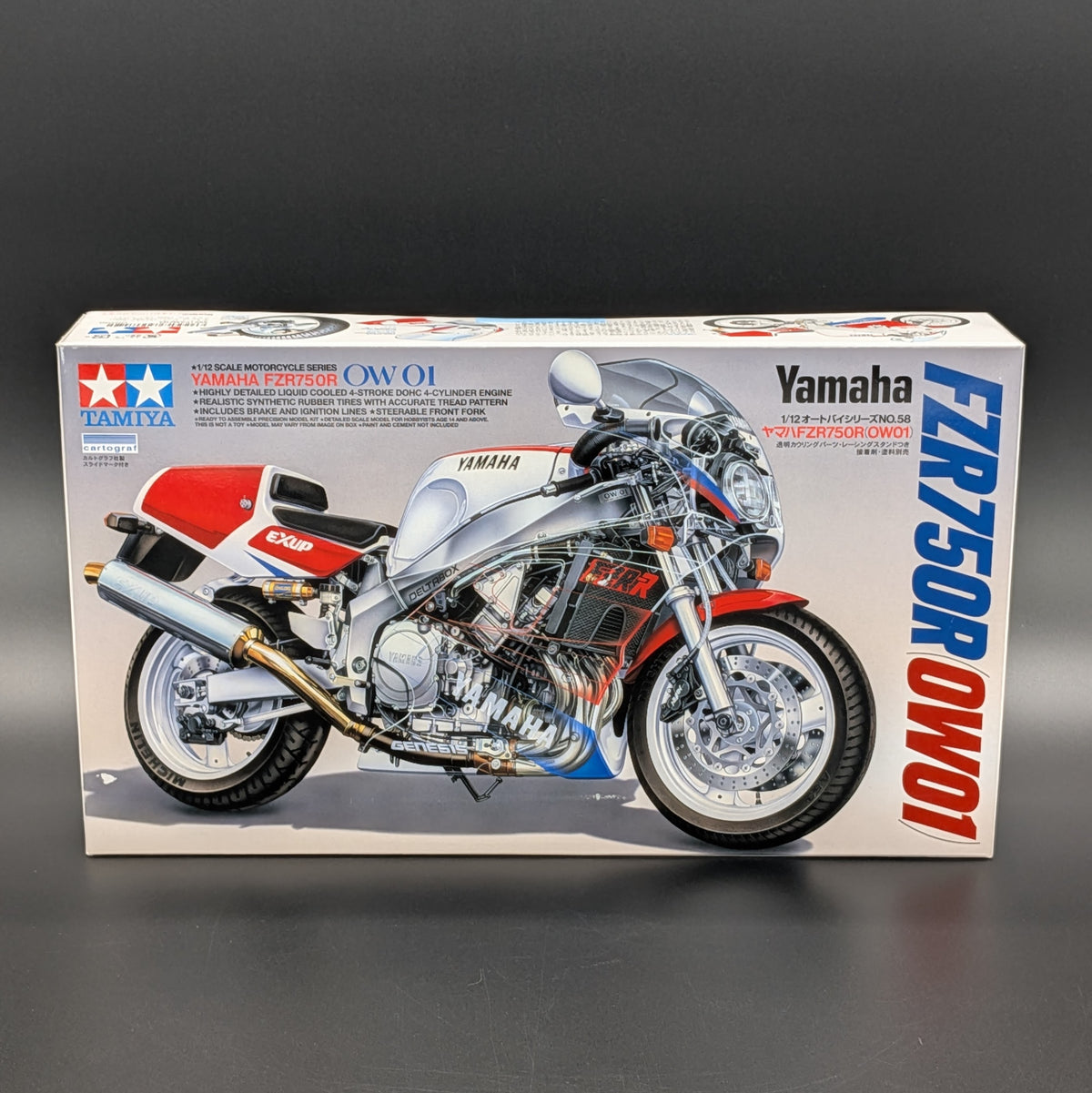 Tamiya model kit box for Yamaha FZR 750 R OW-01, featuring a printed side view of the motorcycle on a white package against a dark gray background.