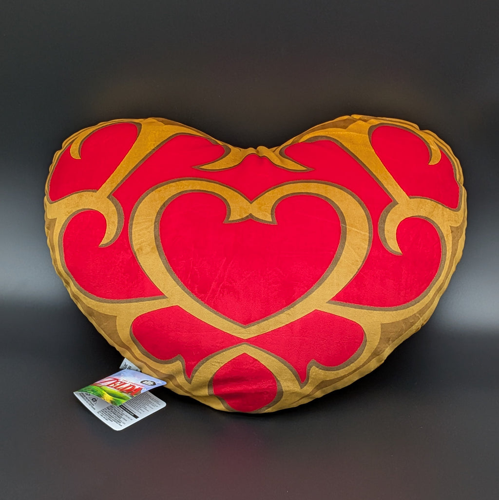 The Legend of Zelda, Link's Heart Container is a heart-shaped decorative plush/pillow with a red and gold pattern, shown face on, on a dark grey background with its retail tag attached.