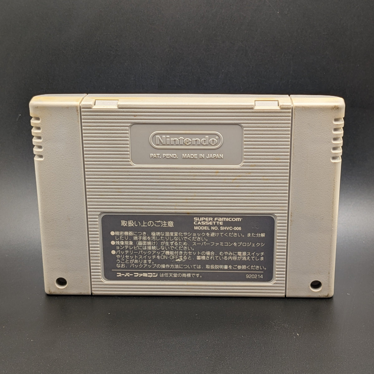 Thoroughbred Breeder video game cartridge for Nintendo's Super Famicom (SFC) Entertainment System, shown from the back, standing up and shows slight yellowing on the back. Pictured on a dark grey background.