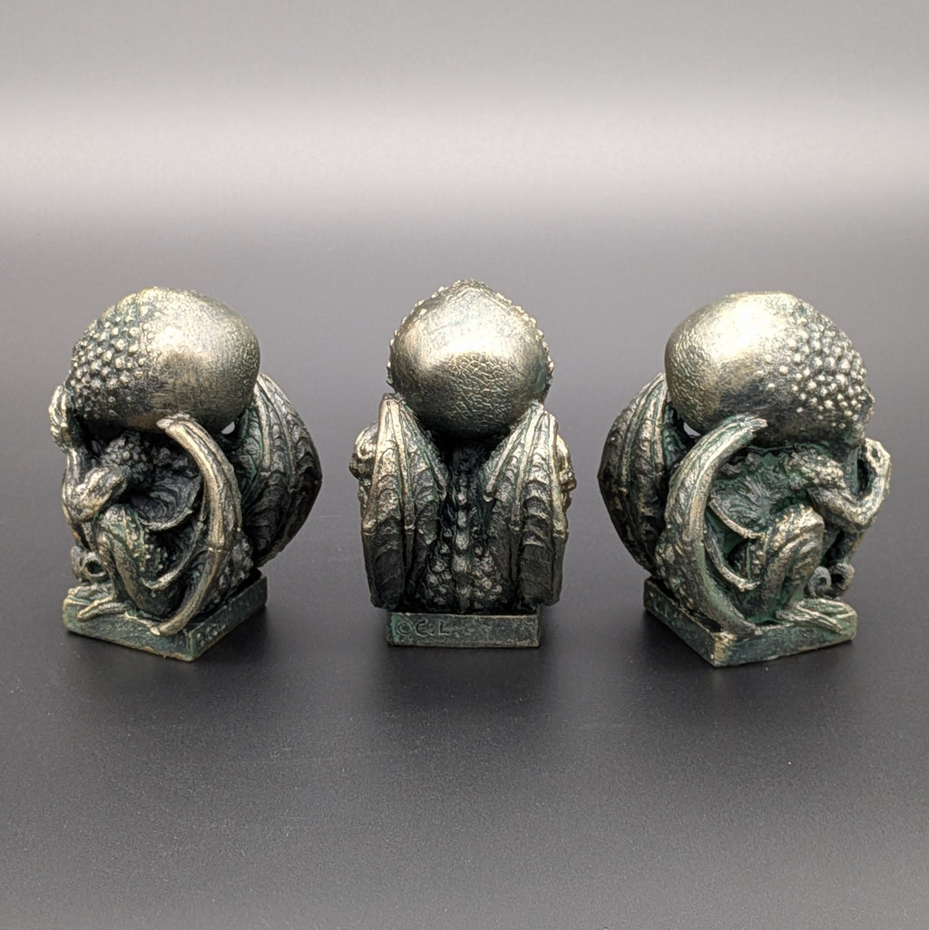 Three small polyresin fantasy creature figurines with textured spherical heads and curled tentacles (Cthulhu), pictured from behind and displayed against a dark grey gradient background.