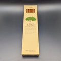 A tall, narrow beige cardboard box for Tombow 2B Recycled pencil, featuring a green tree illustration and Japanese text, set against a dark grey background.
