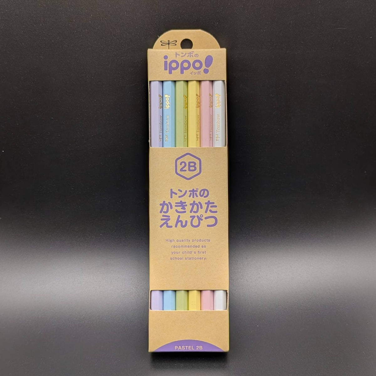 A package of 8 pastel-colored pencils in a tan cardboard sleeve with Japanese text, shown on a dark gray background.