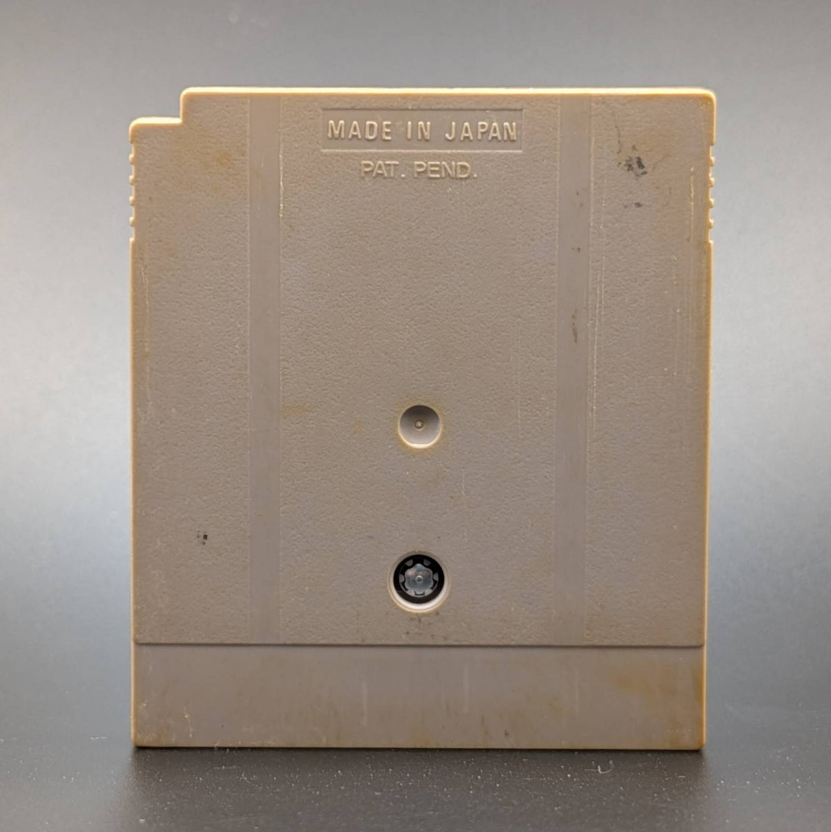 A vintage beige plastic Game Boy Cartridge shown from the back, featuring 'MADE IN JAPAN' and 'PAT. PEND.