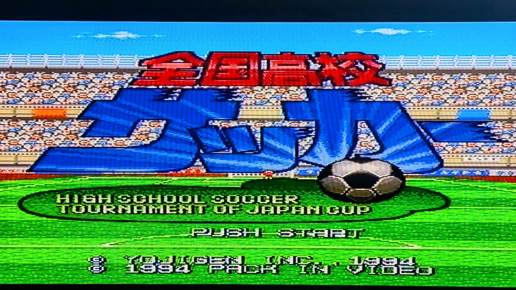 The video game title screen for Nintendo's Zenkoku Kōkō Soccer on the Super Famicom (SFC), the 1994 High School Soccer Tournament of Japan Cup, featuring large blue and red Japanese text over a soccer field with a soccer ball graphic. This shows the game is tested and working.