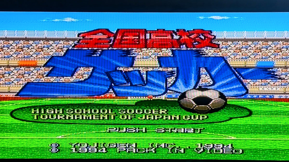 The video game title screen for Nintendo's Zenkoku Kōkō Soccer on the Super Famicom (SFC), the 1994 High School Soccer Tournament of Japan Cup, featuring large blue and red Japanese text over a soccer field with a soccer ball graphic. This shows the game is tested and working.