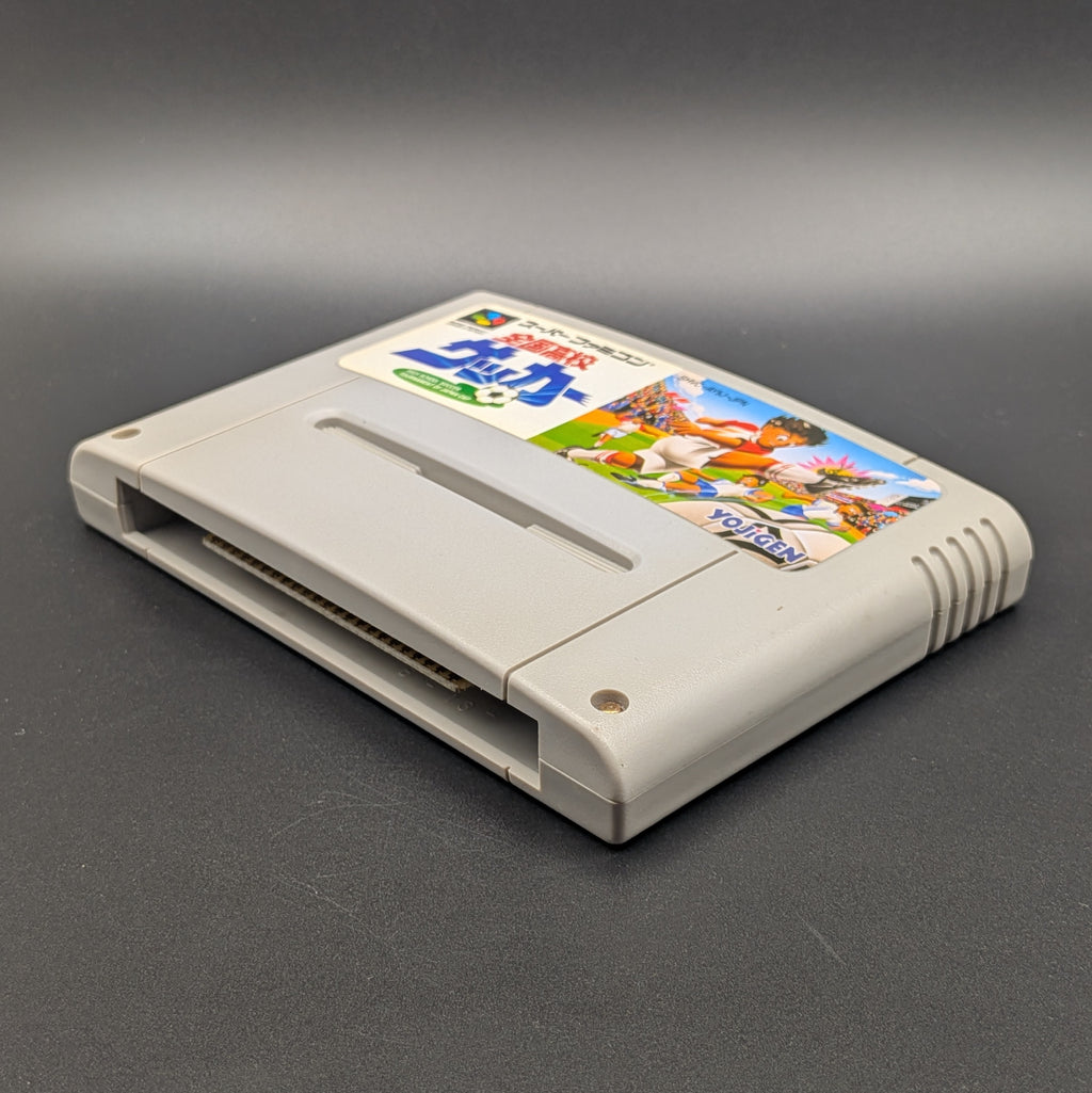 Zenkoku Kōkō Soccer video game cartridge for Nintendo's Super Famicom (SFC) Entertainment System, shown laying on its back with the label facing upwards. Showing the right hand side and bottom slot. It sits on a dark grey background.