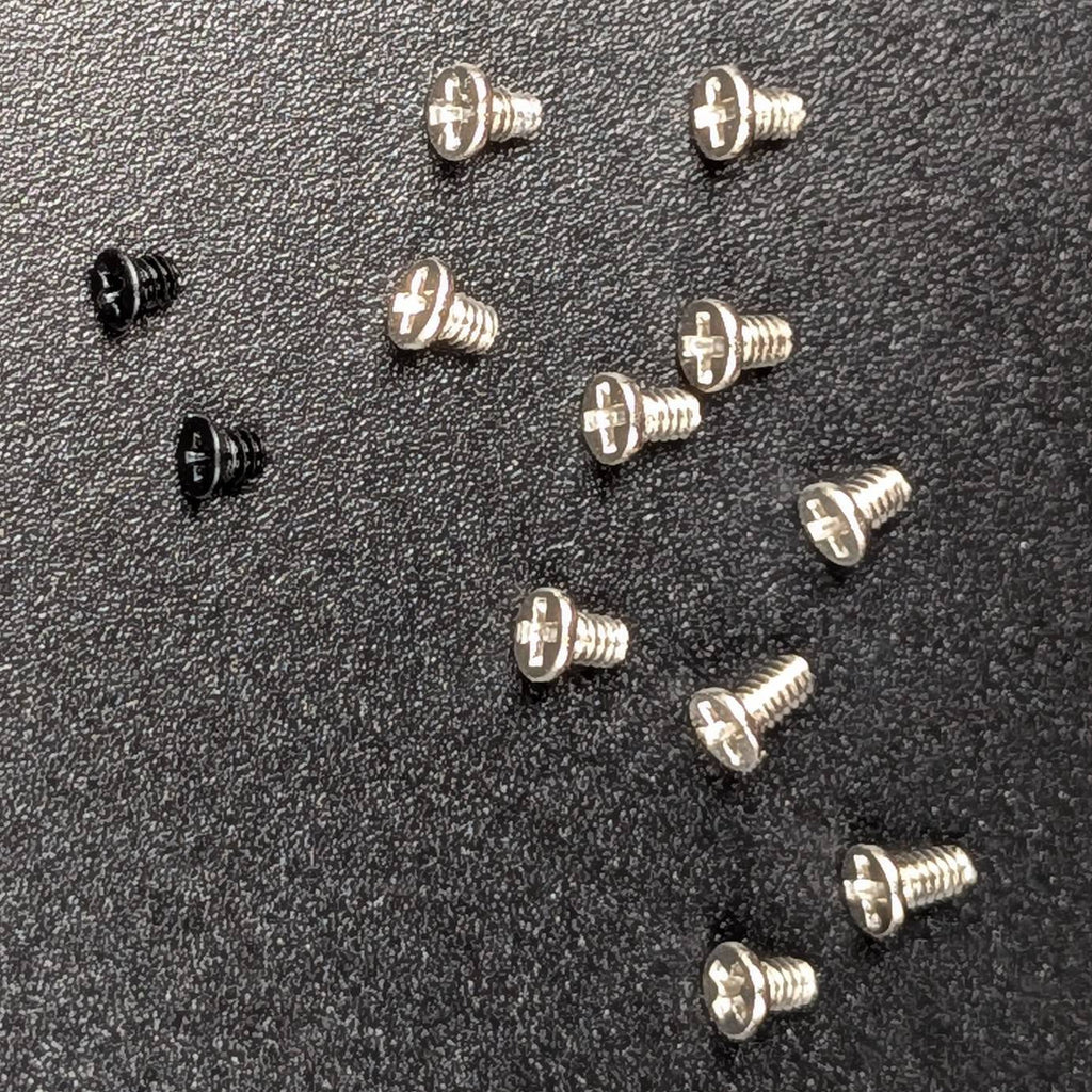Twelve small screws on a textured black background, with ten silver screws and two black screw.