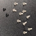 Twelve small screws on a textured black background, with ten silver screws and two black screw.