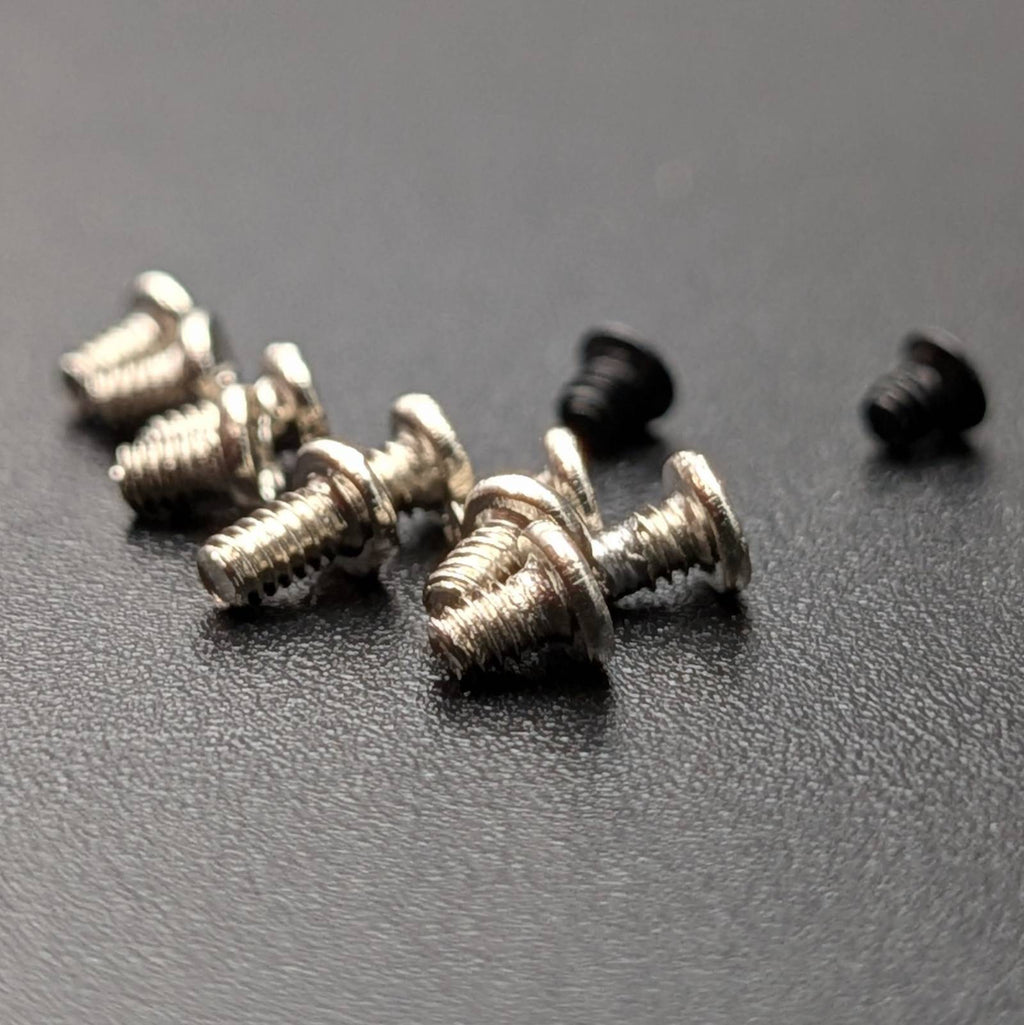 Twelve small screws arranged on a dark textured surface.