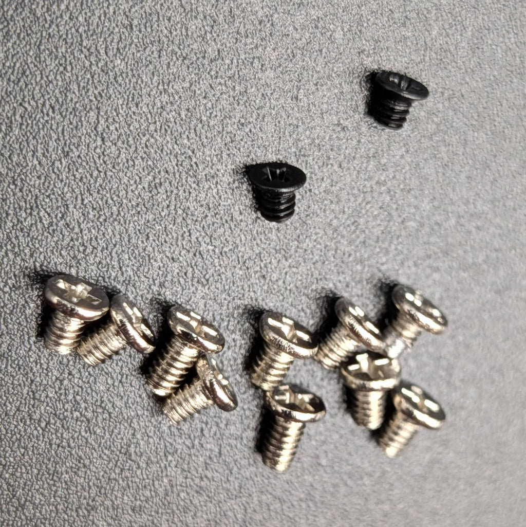 A group of small screws arranged on a textured gray surface.