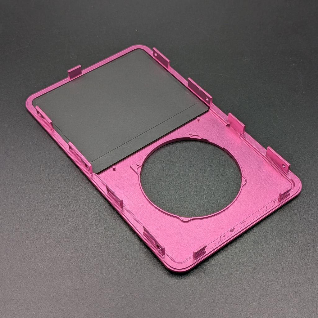 A bright pink protective case frame or shell with a circular cutout and mounting tabs, shown on a dark gray background.