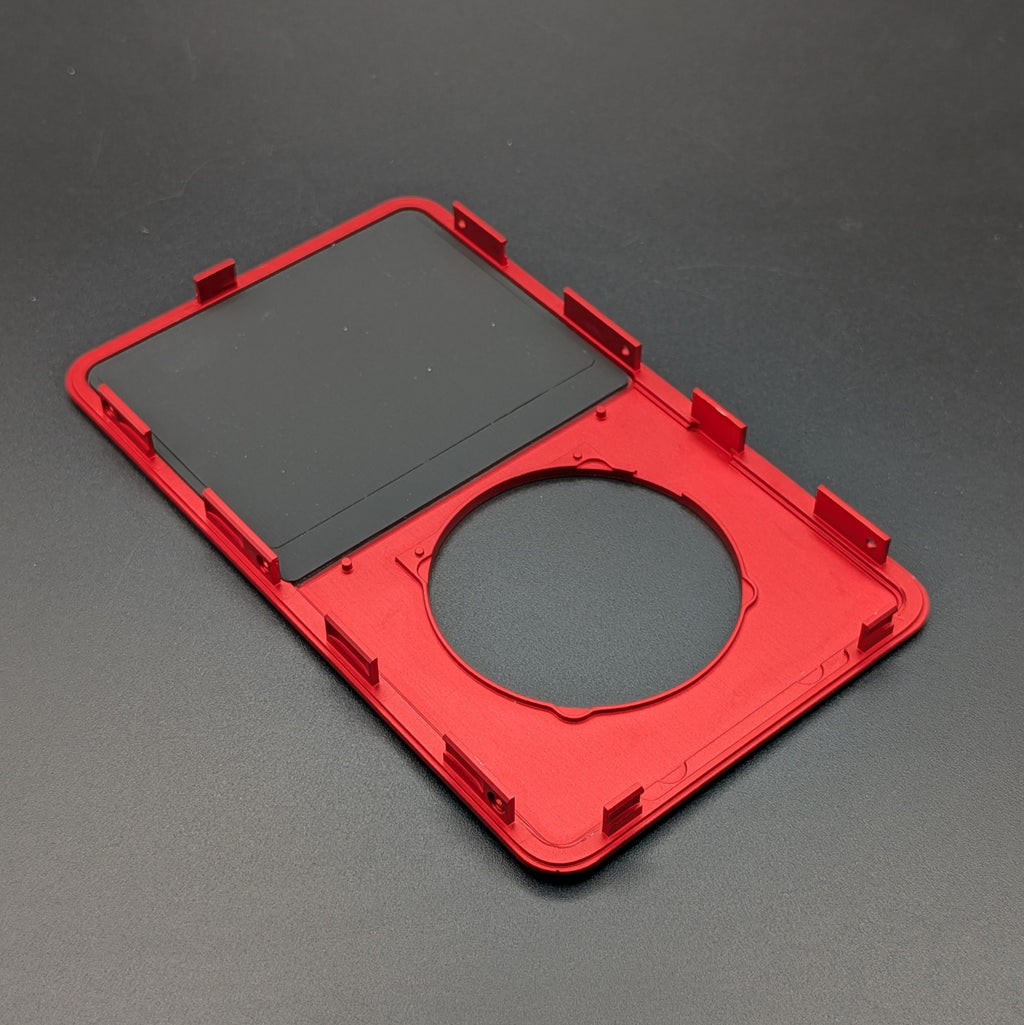 A red plastic replacement frame or bezel with a circular cutout and a black rectangular insert, shown on a dark gray background.