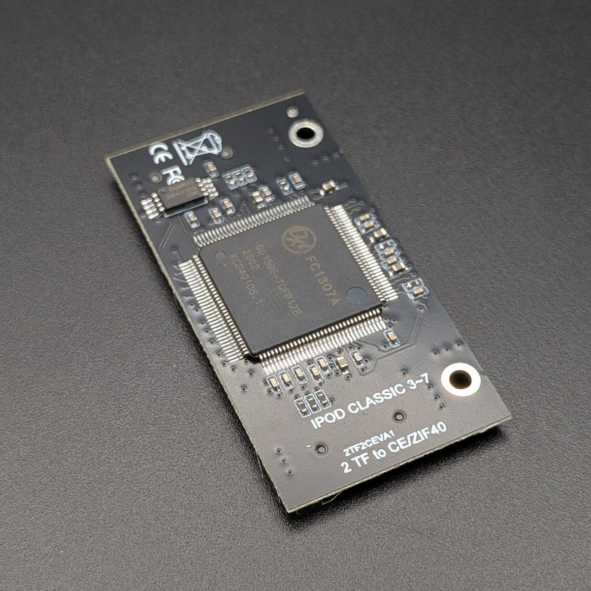 A black electronic circuit board featuring a central processor chip, photographed on a dark textured background.