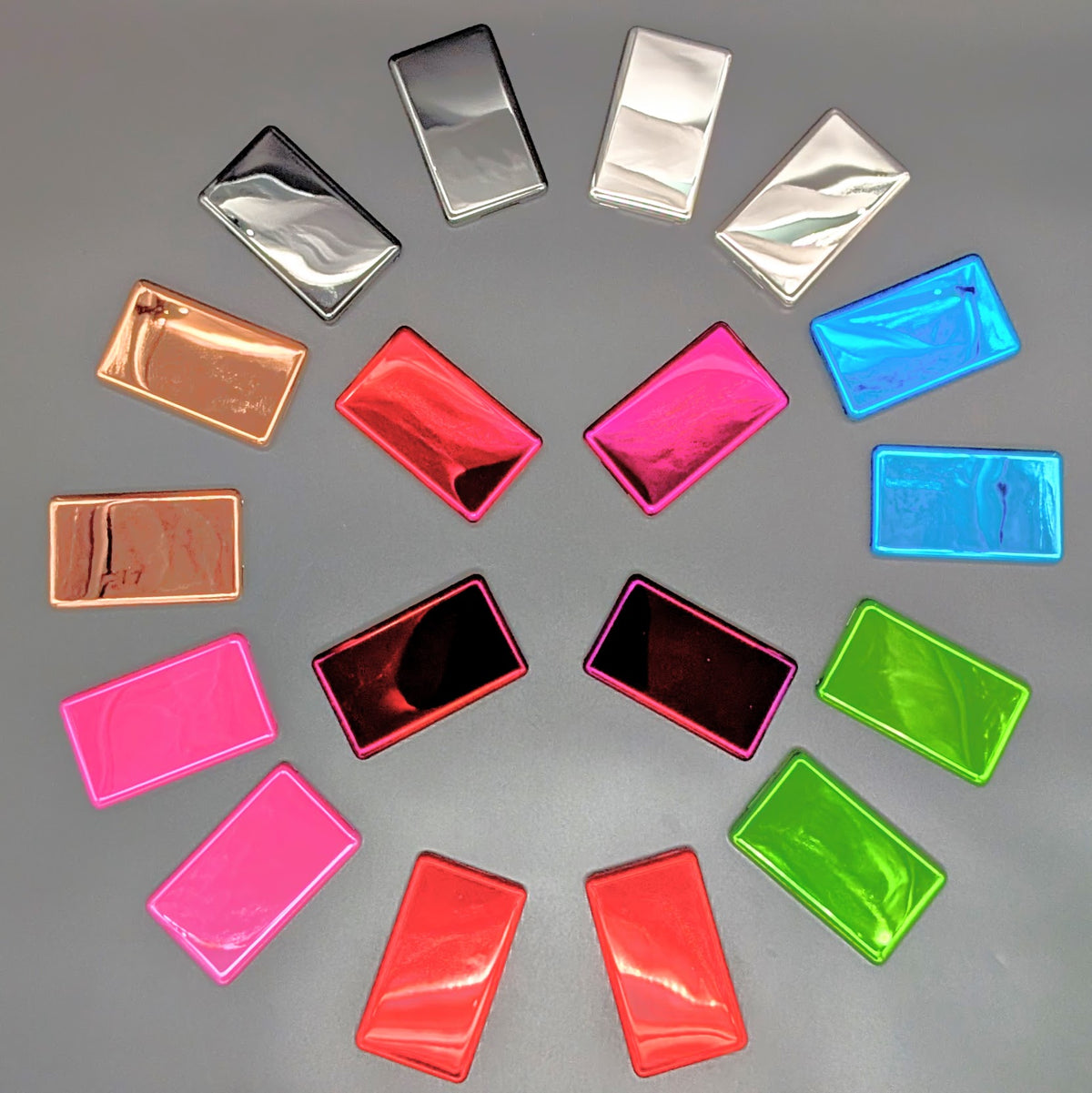 A collection of rectangular metallic iPod back plates in various colors, including pink, red, green, blue, silver, and copper, arranged in a circular pattern on a neutral gray background.