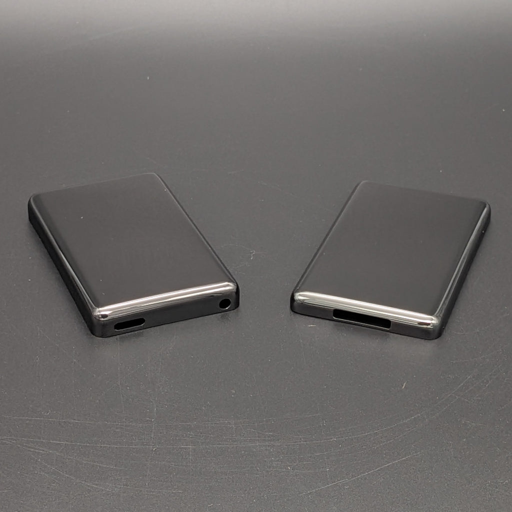 Black rectangular iPod back plates, shown from the back on a dark gray textured surface.
